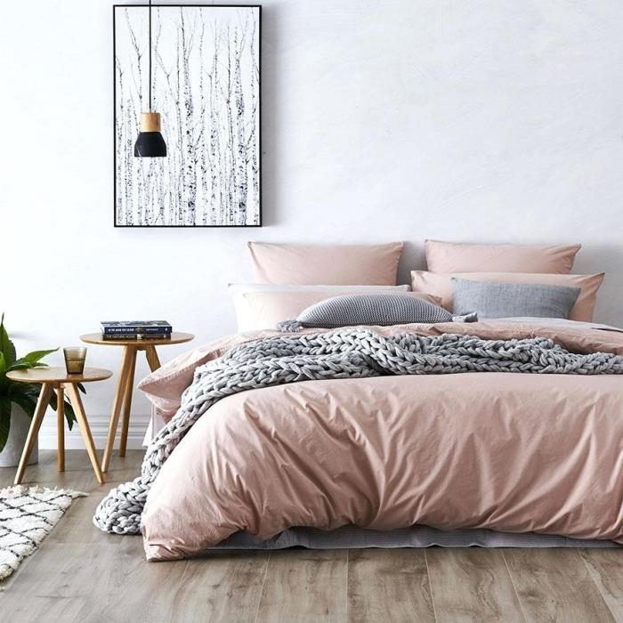 rausvos ir pilkos spalvos miegamojo modelis su baltomis sienomis su tamsaus medžio parketu, didele lovos apdaila su rausvos spalvos lino ir pilkomis pagalvėlėmis