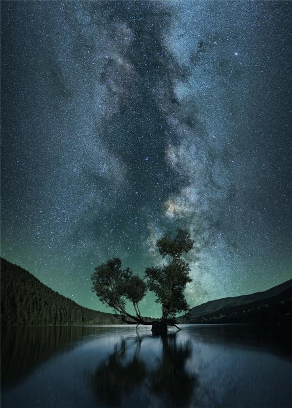 kraštovaizdžio nakties tapetai su kalnų viršūnėmis ir medžių siluetų atspindžiai ežere po žvaigždėtu dangumi