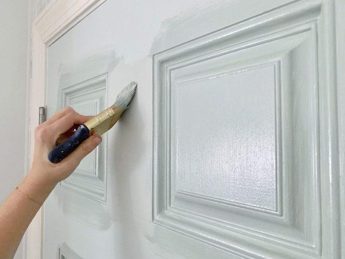 bir kapıyı fırça ve beyaz boya ile boyayın