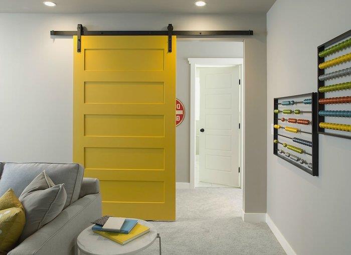 sarı minderler ve gri kanepeler ile oturma odasında parlak sarı renkte sürgülü bir iç kapıyı boyayın