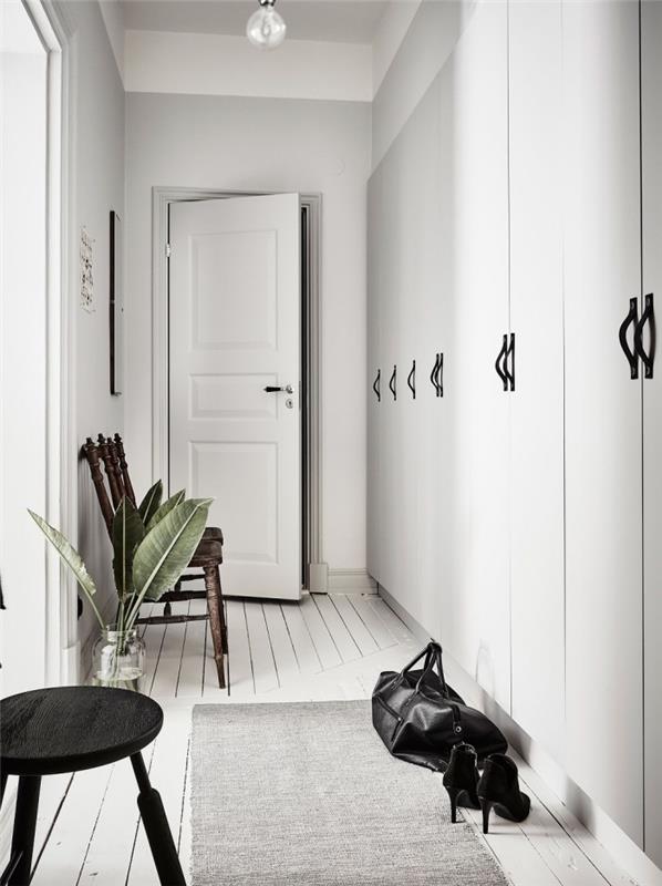 Hodnik v skandinavskem slogu z belimi stenami s črnimi odtenki na pohištvu, hodniška omara z vgrajenim shranjevanjem