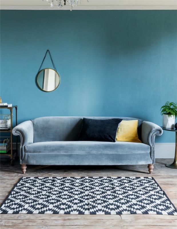 duvarlarda ve tasarım mobilyalarda rengi azaltan tavuskuşu mavisi oturma odası, küçük duvar aynası duvarın zenginliğini ve parlaklığını vurgular.