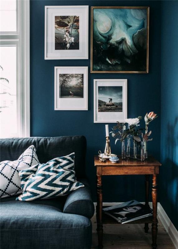 anties mėlyni dažai, mėlyna sofa ir mažas senovinis medinis stalas, meniniai paveikslai