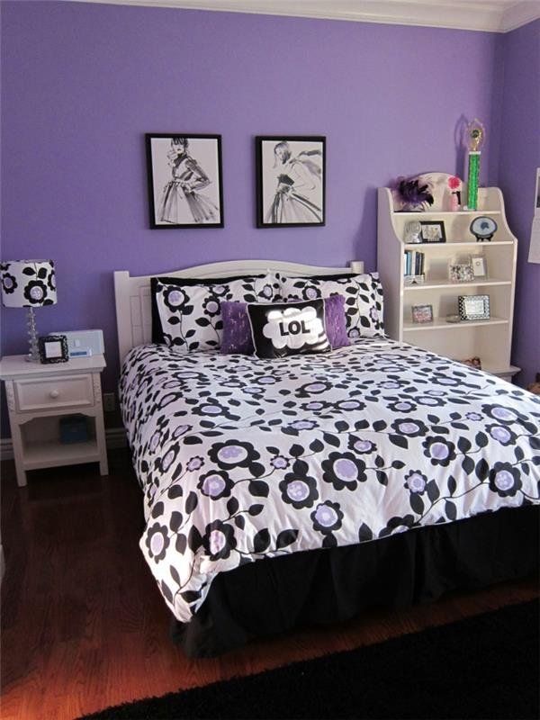 dekor spalnice za najstnice z lila stenami, moderna barva spalnice moderne deklice, dve sliki s črnimi okvirji nad posteljo, posteljna prevleka z velikimi vzorci marjetice v beli, črni in lila barvi, kotna omara v barvi slonovine