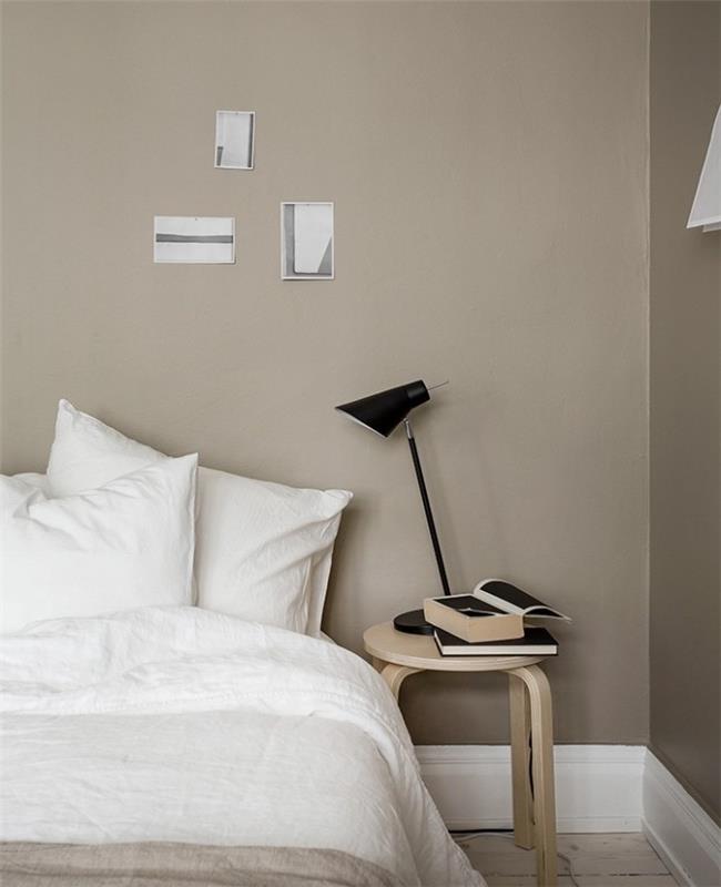 svetlo siva barva na stenah spalnice v sivo -beli barvi, belo laneno posteljno perilo, črna miza iz svetlega lesa, oblikovalska črna nočna svetilka