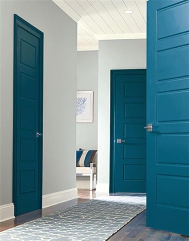 koridoru ve kapıları mavi boyalı duvarlarda nötr renkte boya