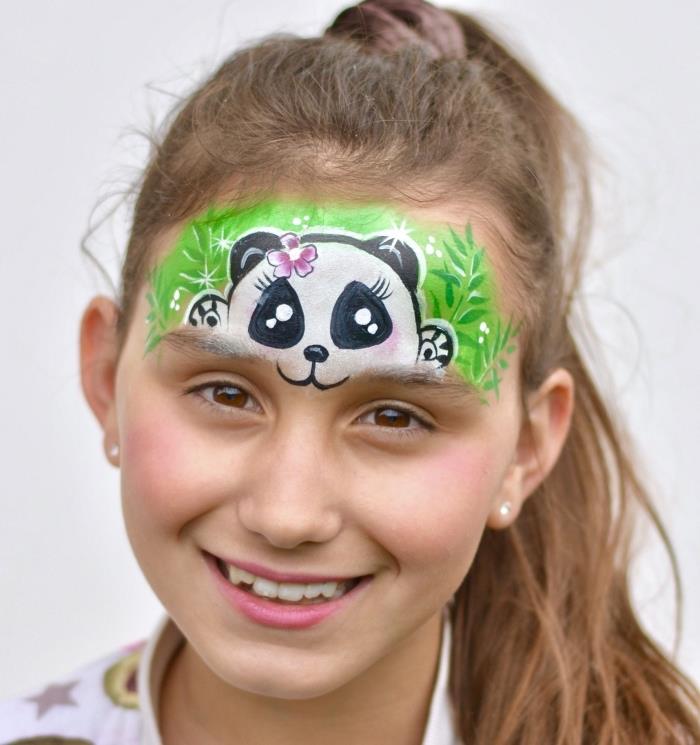 Çocuklar için ne kadar kolay cadılar bayramı makyajı, kafasında çimenlere gizlenmiş pembe çiçekli mini panda tasarımında küçük bir kızın alnına çizim