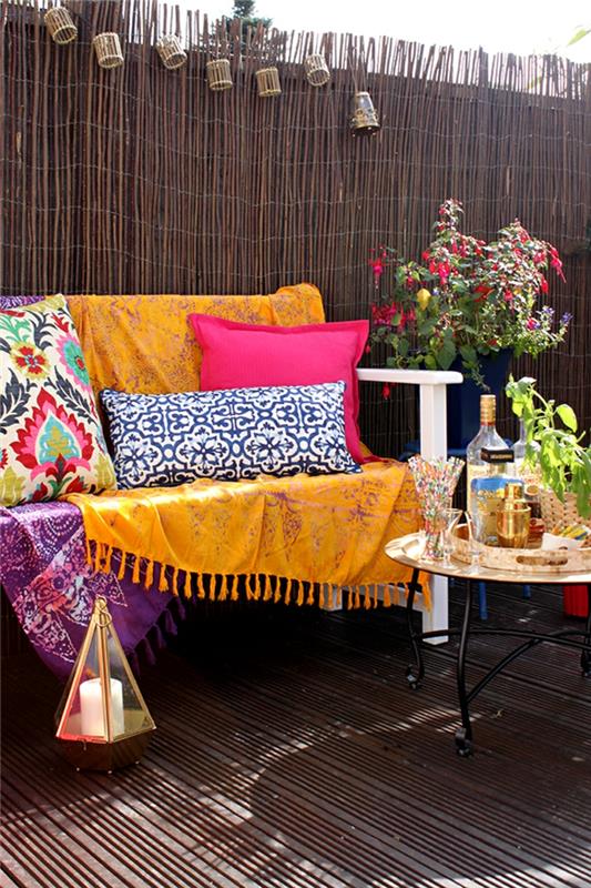 škrlatna barva na vrtu ali terasi s pohištvom, polnim pisanih blazin