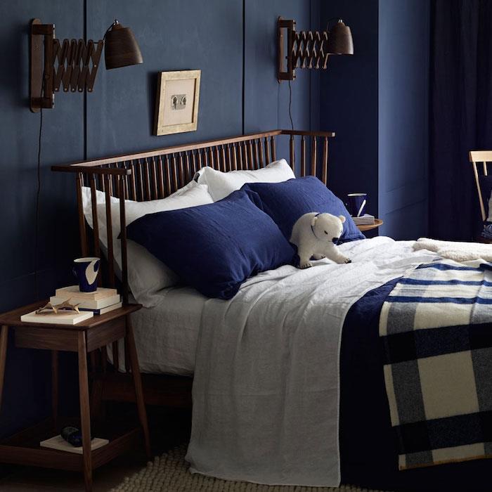 modro -beli dekor spalnice z modro -belim posteljnino, nočno omarico in lesenim vzglavjem, originalnimi starinskimi svetilkami