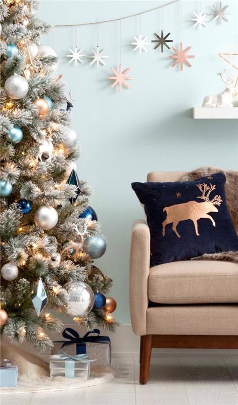 kumaş ve koyu ahşap mobilyalarla döşenmiş pastel mavi duvarları olan bir oturma odasında modern iç tasarım, metalik süslemeli Noel ağacı dekorasyonu