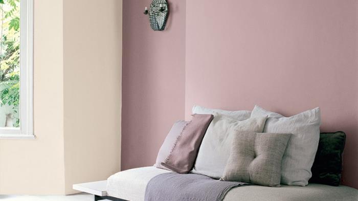 šviesiai rožinio miegamojo su pasteline geltona siena ir dideliu langu pavyzdys, medinis poilsio suoliukas su dekoratyvinėmis pagalvėmis