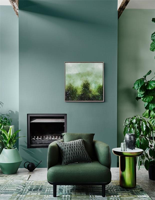 Bir oturma odası için 2020 renk trendi, yeşil mobilyalar ve mat siyah vurgularla döşenmiş yeşil duvarlara sahip bir oturma odası örneği