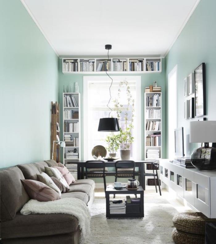 jūra žalia svetainė su pilka sofa ir rožinėmis ir pilkomis pagalvėmis, baltu kilimu, dizainerio balta televizoriaus spintelė, balta knygų spinta, stalas ir anglies pilka kėdė