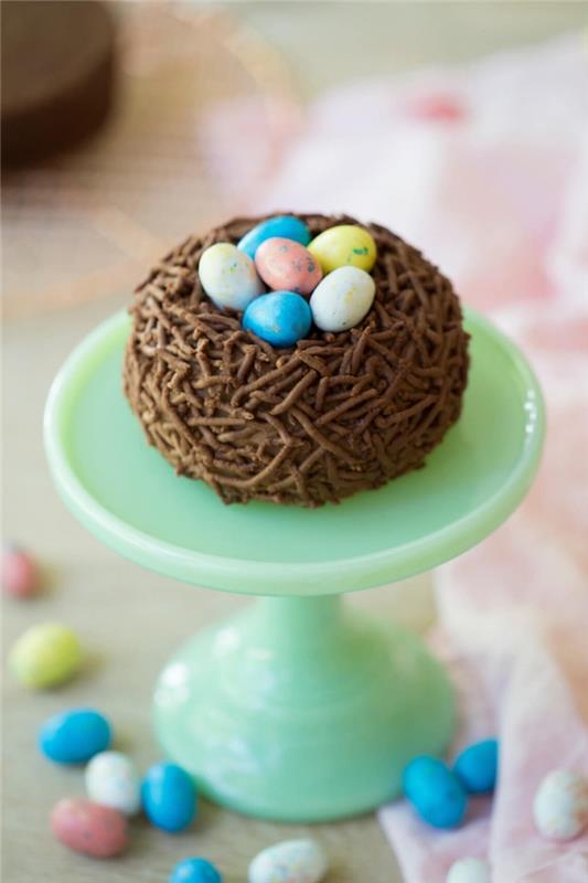 čokoladno velikonočno gnezdo piškote na vrhu pastelne zelene torte s čokoladnimi jajci, klasična velikonočna torta