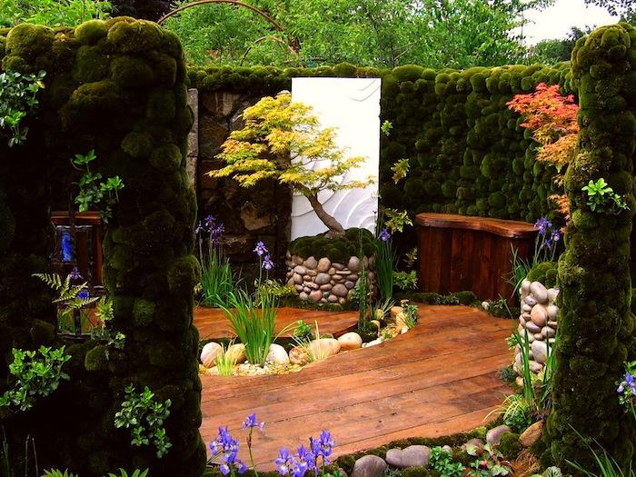 primer čistega japonskega vrta s steno iz maha, lesenim parketom in rastlinami in cvetjem
