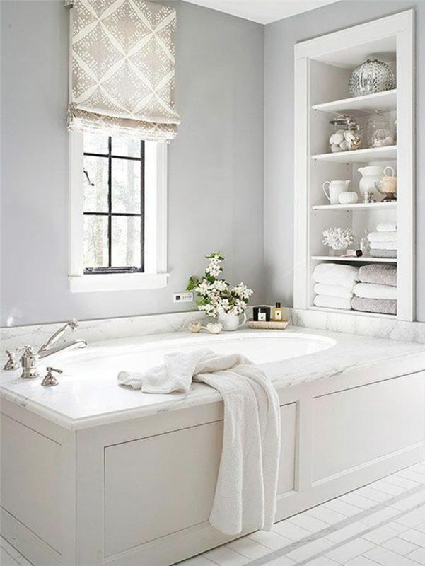 maži vonios kambariai su didele vonia baltos spalvos ir sandėliavimo patalpos su lentynomis, įkištomis į sieną