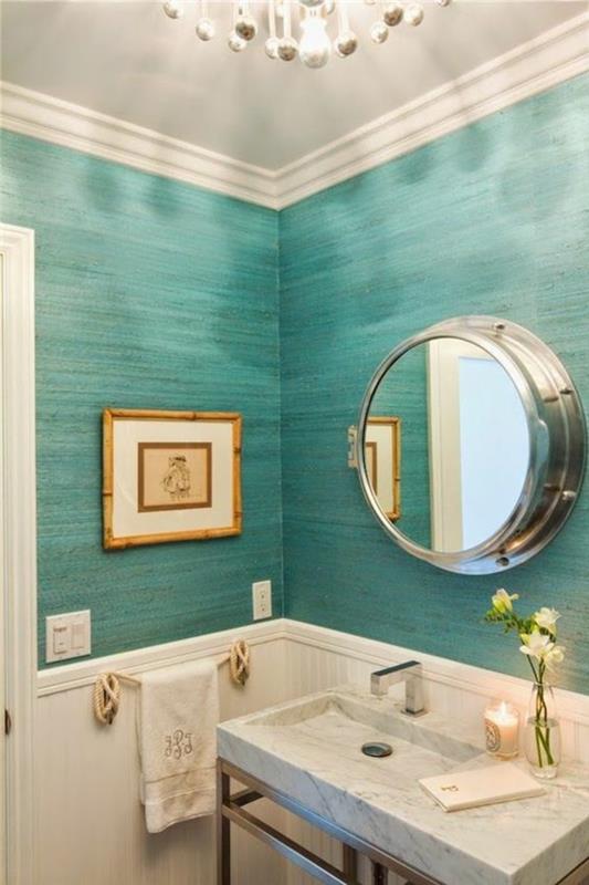 labai mažas vonios kambarys su iliuminatoriaus stiliaus veidrodžiu su paveikslu ant sienos vandenyno žalios spalvos krištolo liustra