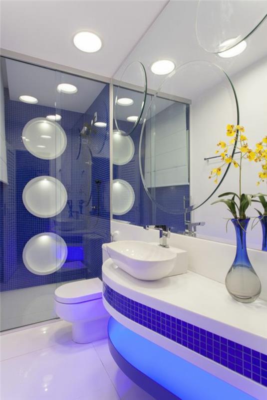 mažas tamsiai mėlynos ir baltos spalvos vonios kambarys su dideliais burbulų raštais ant dušo sienos