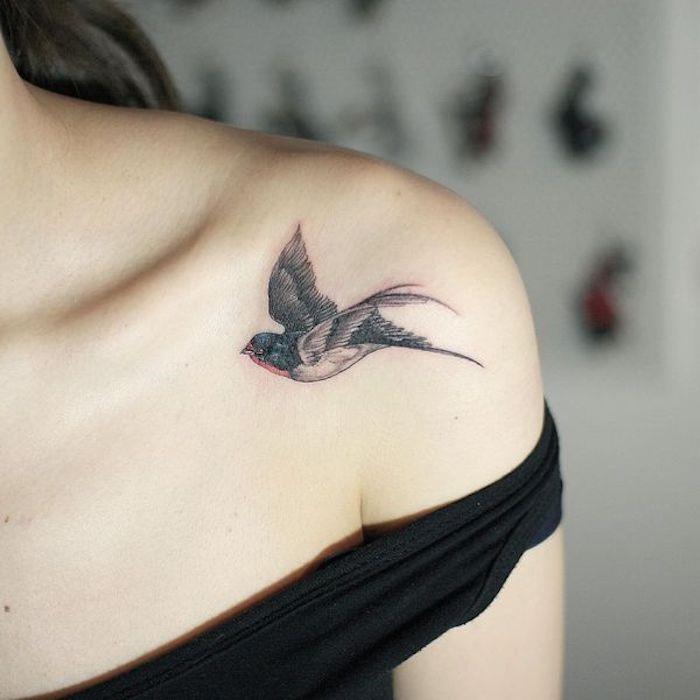 Ženska tetovaža na rami, podoba ptice pod ključno kostjo, simbol svobode v rdeči in črni barvi