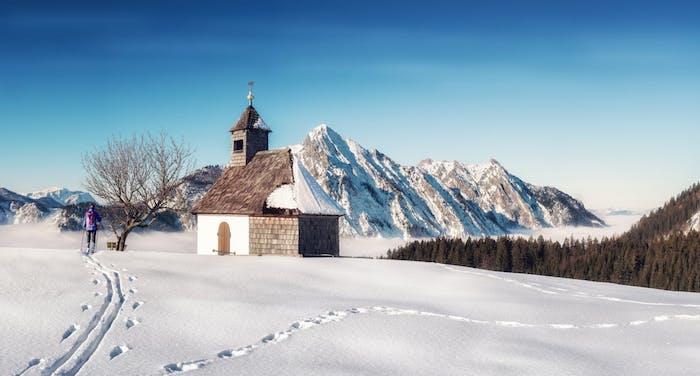 snieguoto kraštovaizdžio idėja, sniegu padengta kalva sniego padengto kalno viduryje, bažnyčia, maža paprasta šventykla