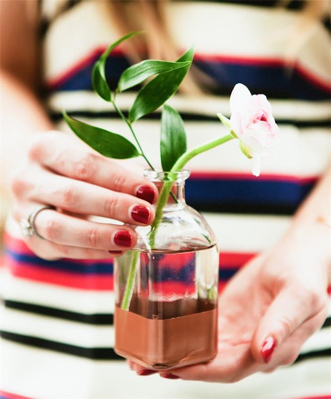 İçinde bir çiçek sapı olan küçük bir cam şişede kahverengi renkli bir arka plana sahip vazo, bir ev dekorasyonu yapmak için yaratıcı aktivite