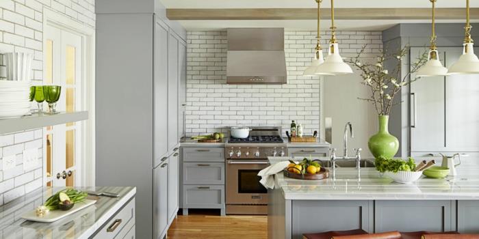 pilka ir medinė virtuvė, keturios baltos lempos, pilka virtuvės sala, baltos metro plytelės, žalia vaza