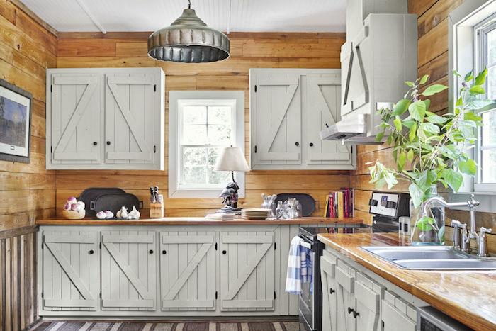 medžio ir baltos virtuvės modelis su šviesiai medine sienų danga, aukšti ir žemi įrenginiai su senovinėmis baltomis spintelių durimis, pilkas ir baltas kilimas, nerūdijančio plieno dulkių siurblys