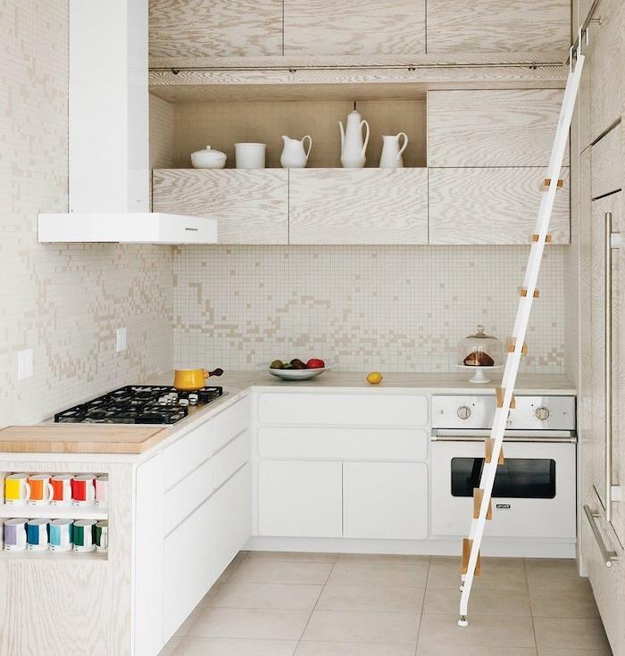 maža balta virtuvė l su balta pagrindine spintele ir medine viršutine spintele, baltu dulkių siurbliu, smėlio spalvos plytelėmis, baltos ir smėlio spalvos plytelėmis išklotomis virtuvėmis