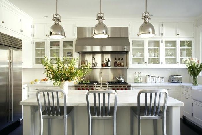 balta virtuvė, pilkos kėdės, chromuotos lempos, įmontuotas šaldytuvas, stiklinės virtuvės spintelės