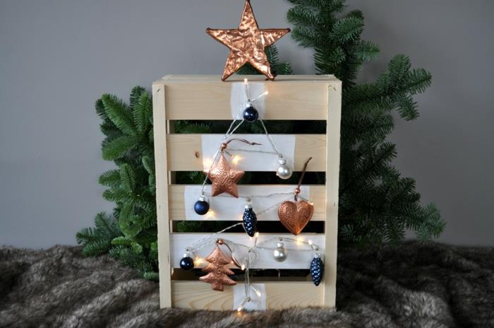 maža medinė paletė, pilkas dirbtinio kailio pledas, vario žvaigždė ant medžio, parodyta paletėje, mėlyni ir variniai ornamentai