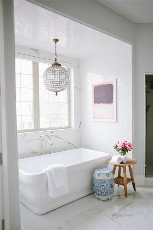 Zen kopalniški dekor, okrogel sijajni lestenec, pravokotna bela kad, tla prekrita z belim marmorjem z nežnimi črnimi rebri