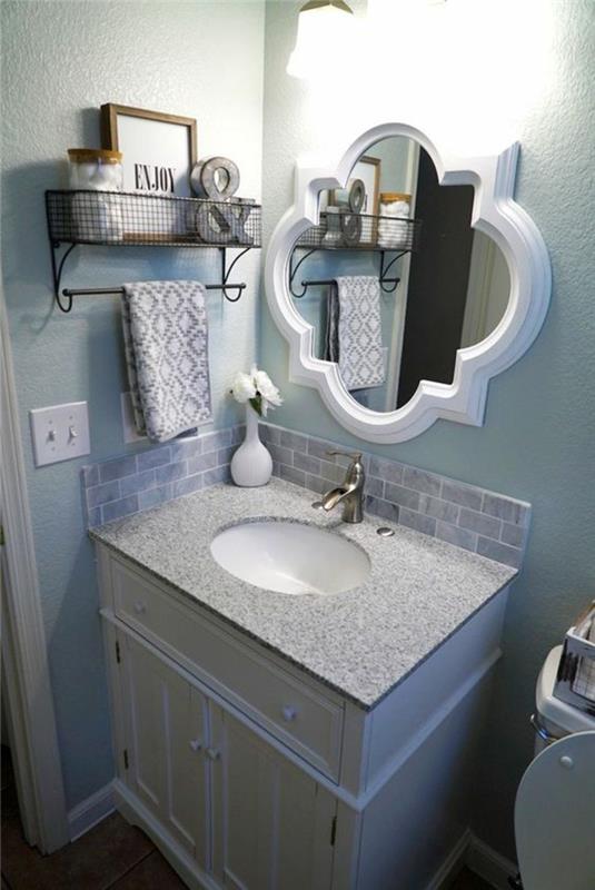 mažas vonios kambarys su baltu barokiniu veidrodžiu ir kolonine spintele baltam praustuvui