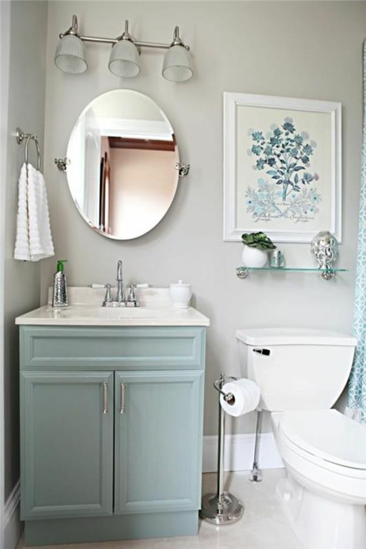 zelo majhna kopalnica z ovalnim ogledalom in mizo srednje velikosti v beli in modri barvi