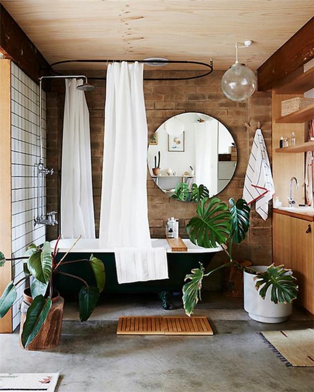 nedideli vonios kambariai su juodomis voniomis ir apvaliais veidrodžiais su baltomis dušo užuolaidomis