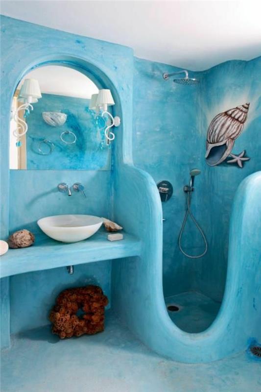 majhna kopalnica v turkizno modri barvi z mornarsko dekoracijo in belim okroglim umivalnikom