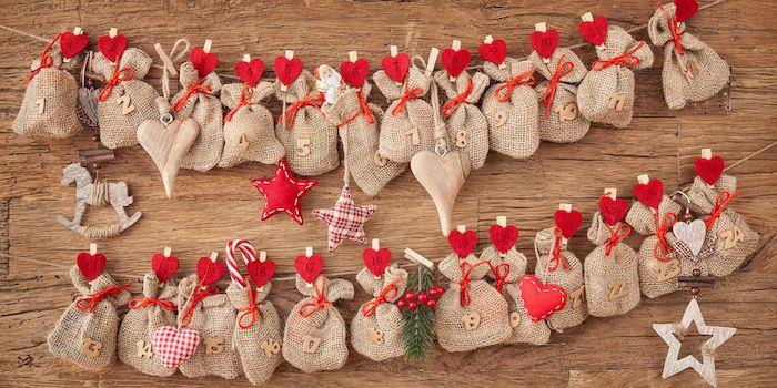 džiuto maišeliai, kabantys ant skalbinių segtukų su raudonomis širdelėmis ant siūlų ir mediniais numeriais, kaimiškas prašmatnus advento kalendorius
