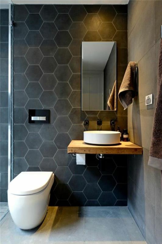 fotografija majhne kopalnice s steno s čebelnjaki v črnem oglju
