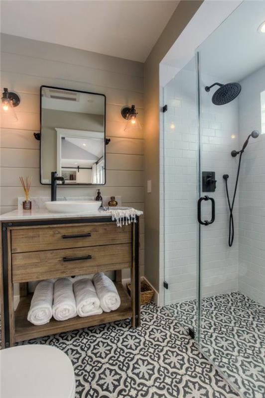 mažas vonios kambarys su languotomis plytelėmis išklotomis baltos ir juodos spalvos juodo metalo veidrodžio juodos spalvos dušais ir juodais baldais be rankovių