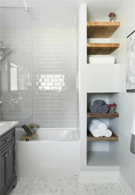 mažas vonios kambarys su šviesiai rudomis medinėmis lentynomis su baltų plytų rašto sienomis