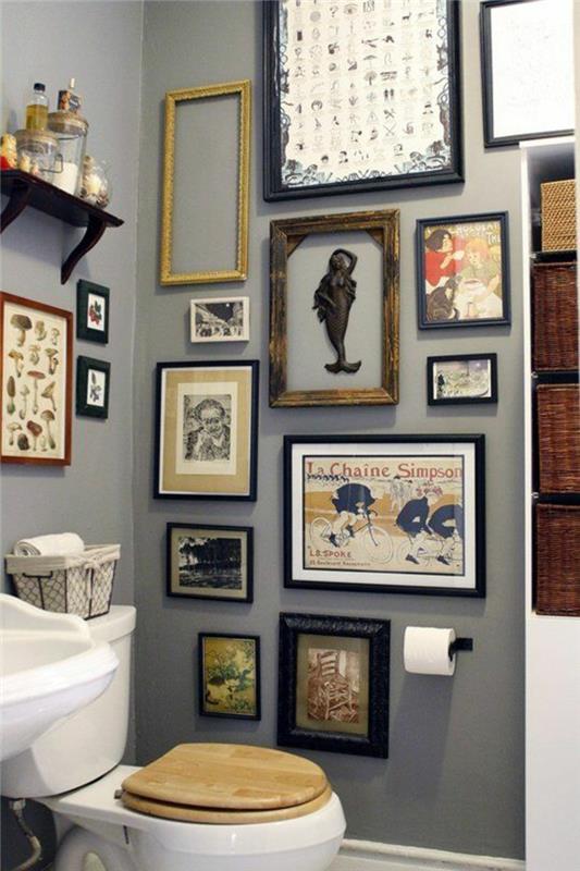 mažas vonios kambarys su pilka siena, papuoštas daugybe paveikslų ir austi rotango krepšeliai saugojimui