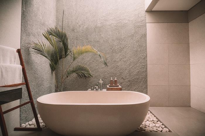 Palma v loncu na zen kamnitih tleh, lestve za nizko shranjevanje, lesena in bela kopalnica, lepa moderna kopalnica