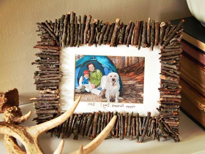 küçük dallardan yapılmış, bir baba, kızı ve köpeğinin bir fotoğrafını içeren, bir çadırın önünde yapılan çerçeve