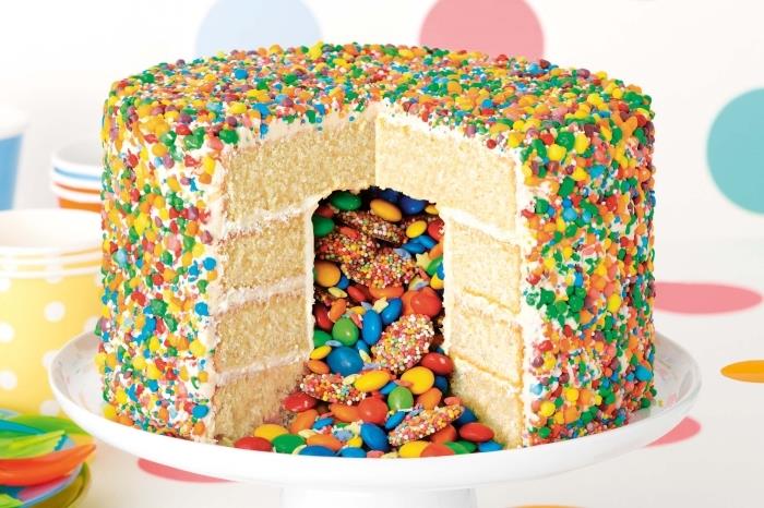 izvirna ideja za večbarvno torto smarties iz biskvita, prelivenega z masleno kremo in okrašenega s sladkornimi konfeti v mavrični barvi