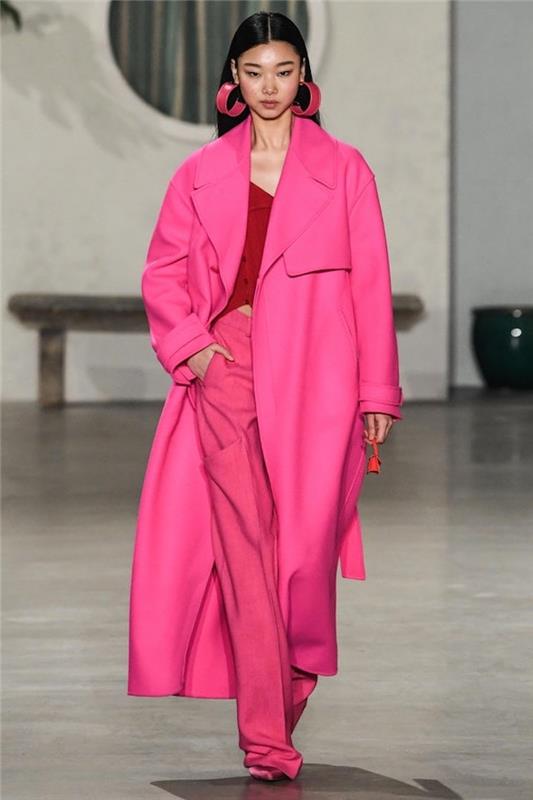 model s črnimi lasmi, ki hodi po vzletno -pristajalni stezi, oblečena v rožnato obleko, modni trendi 2019, veliki obročki v roza barvi