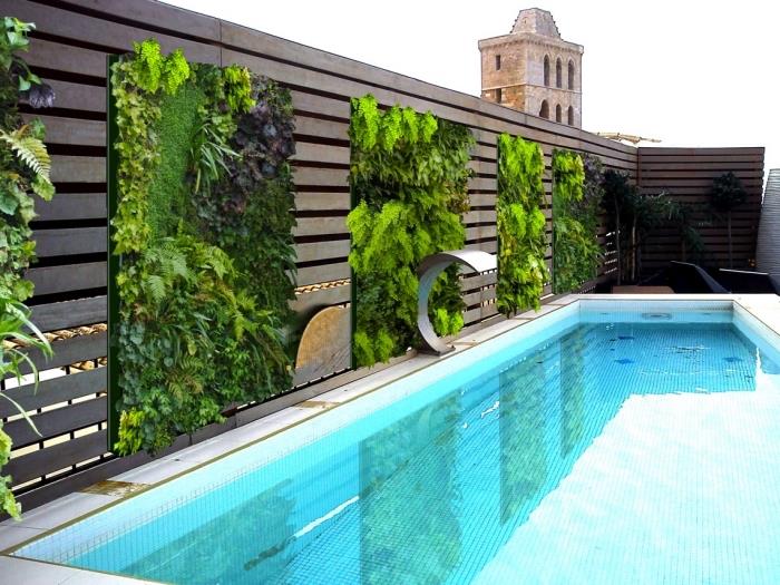 luksuzni bazen z zelenimi stenami, nameščenimi na leseni palisadi, ki delujejo kot rastlinski vetrič, hkrati pa ustvarjajo vzdušje za sprostitev