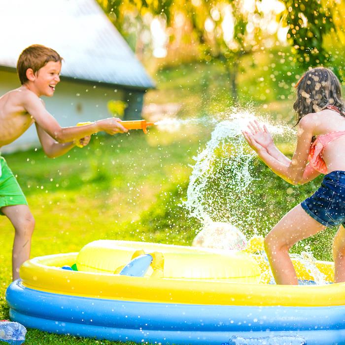 yaz aylarında açık havada 10 yıl doğum günü, yeşil bir çimenlikte şişme bir havuzun etrafında su tabancalarıyla oynamak