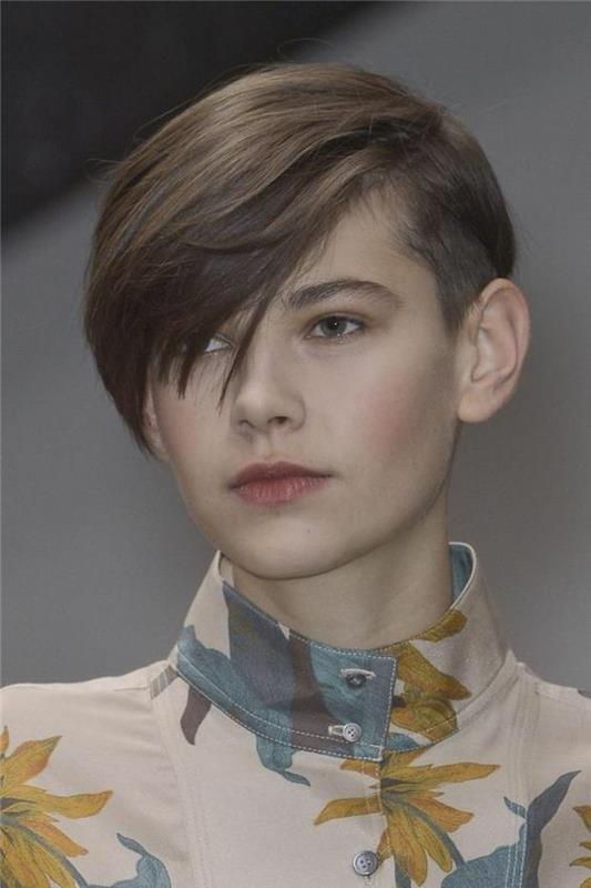 pixie cut, mlada ženska z rjavimi lasmi in moško frizuro, stranske šiške padajo na eno oko, nosi cvetlični top