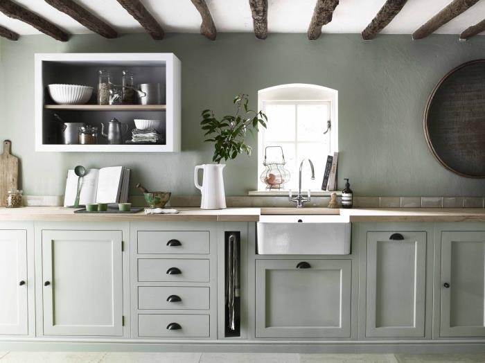 kuhinjska dekoracija s stenami iz žajbljeve zelene barve z belim stropom in lesom, kuhinjsko pohištvo v bledo zeleni barvi