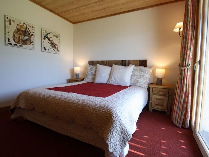 majhna preprosta postavitev glavne spalnice z rdečo preprogo in lesenim stropom