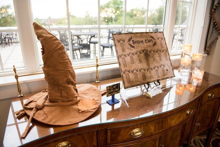 Hario Poterio įkvėptas vestuvių stalo planas, raganos skrybėlė, medinis stalas ir svečių sąrašas iš nusidėvėjusio popieriaus